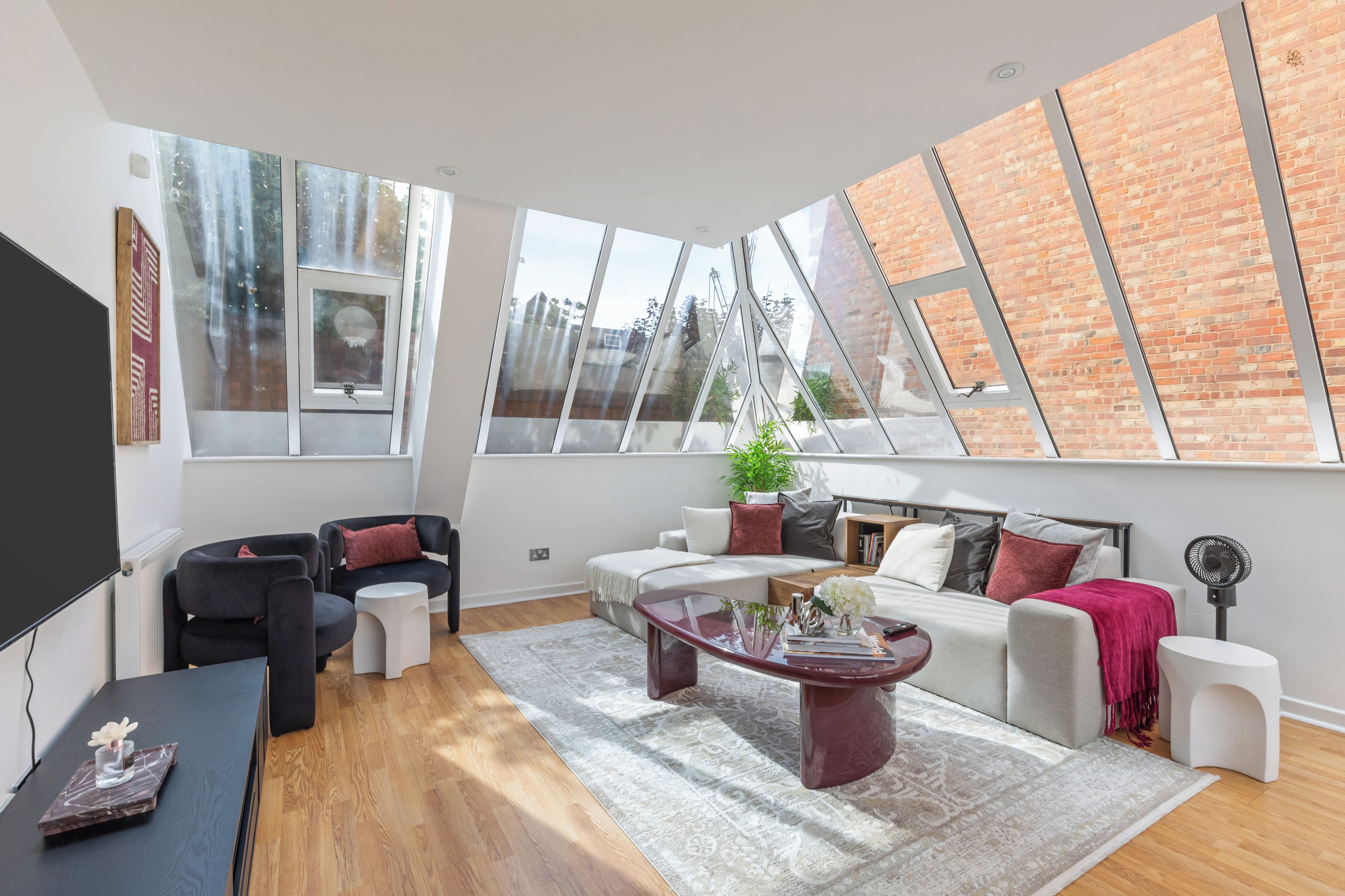 A modern living room with a large window, a sofa, a coffee table, and a TV.