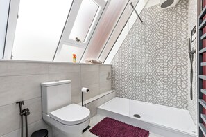 Moderni kylpyhuone, jossa on wc, suihku ja ikkuna.