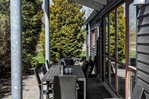 Eine Terrasse im Freien mit Tisch und Stühlen, einem Metallpfosten und einem Gebäude mit großen Fenstern.