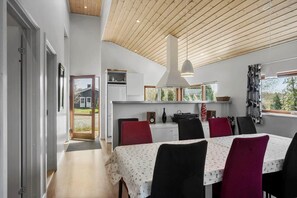 Ein Essbereich mit Holzbalkendecke, weißen Wänden und einem Tisch mit Stühlen.