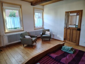 Ein Zimmer mit zwei Sofas, einem Heizkörper, Holzboden und einer Tür mit Spiegel.
