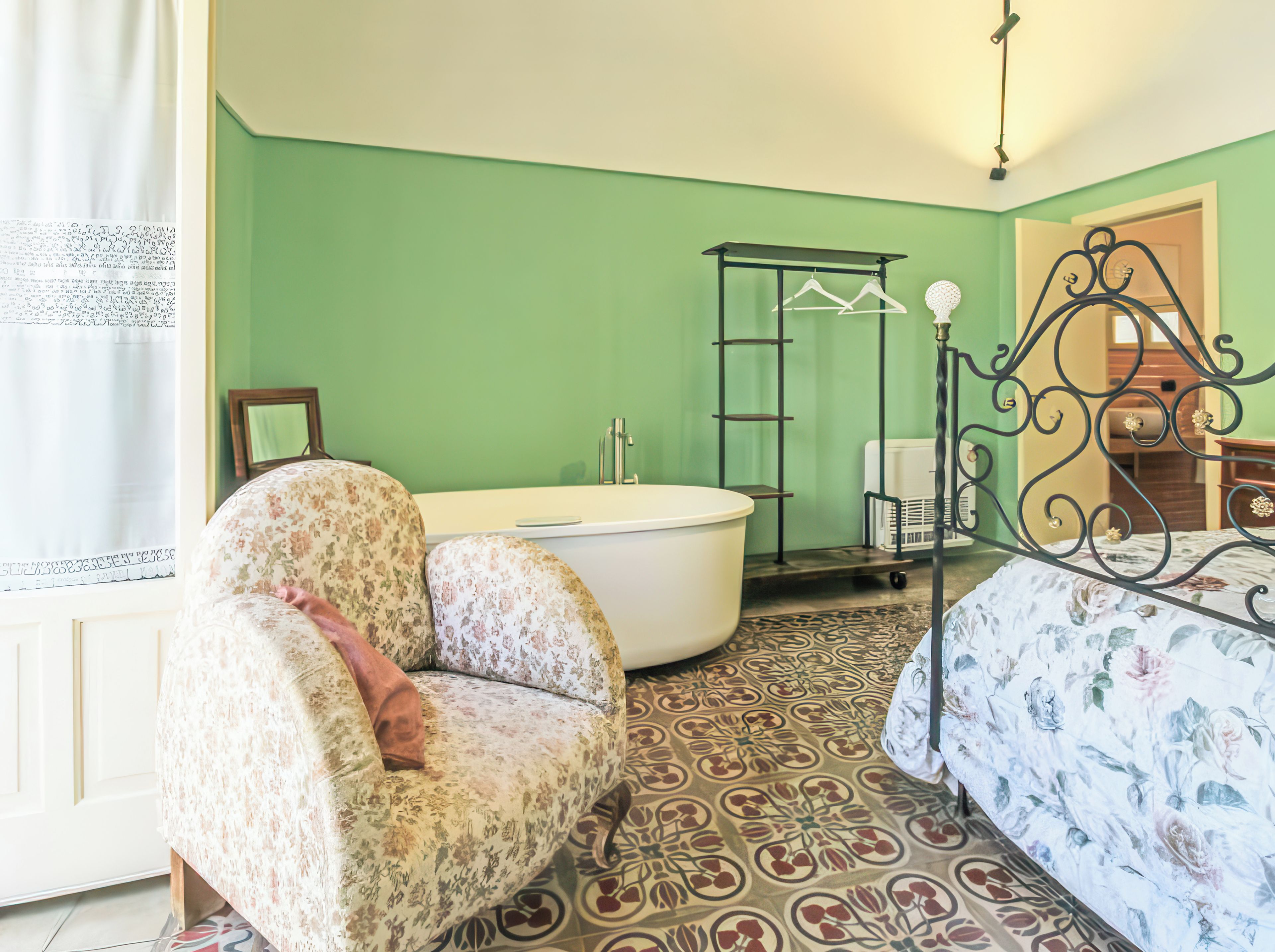 A room with a bed, a chair, a bathtub, and a wardrobe.