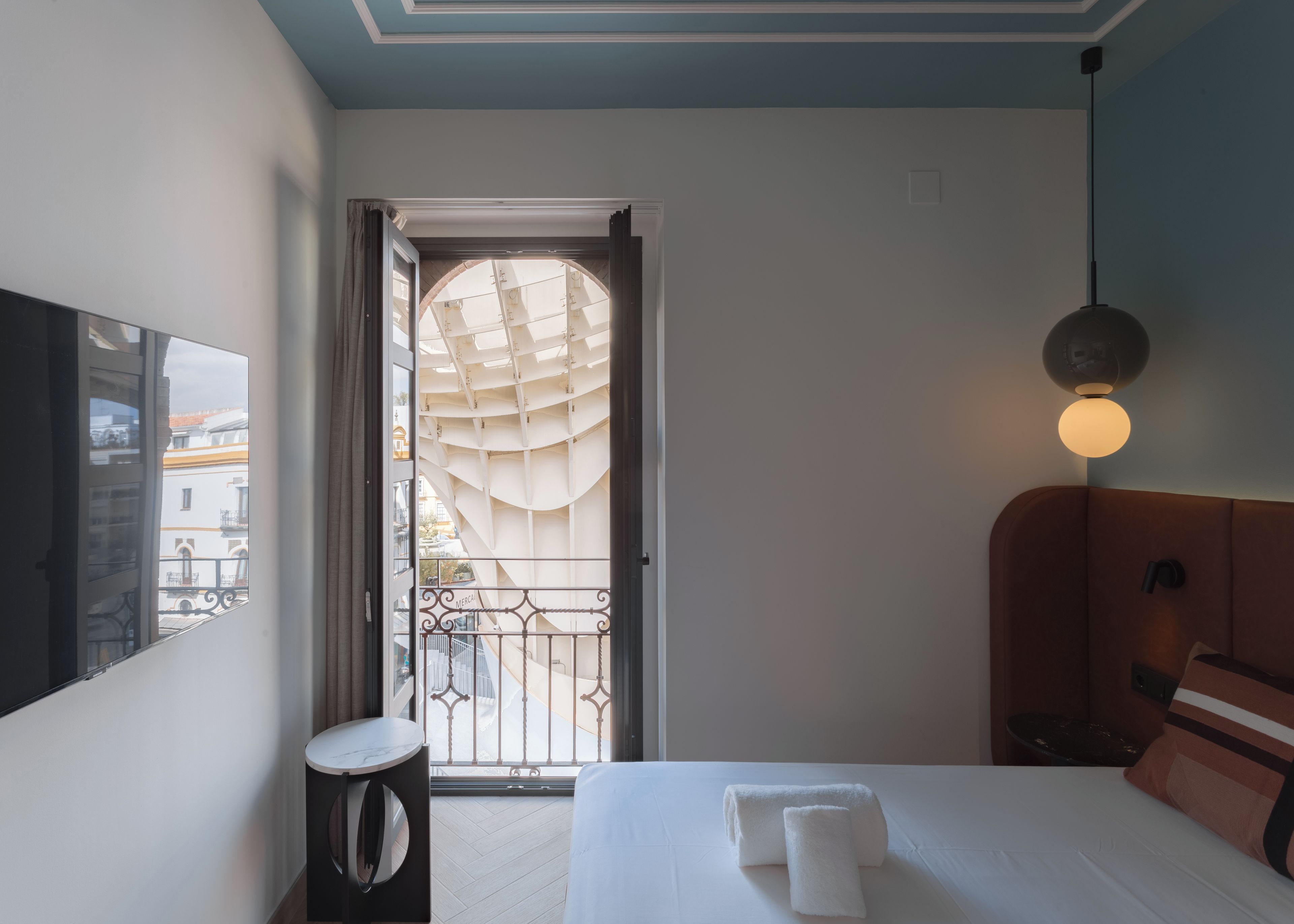 Une chambre d’hôtel avec un lit, une table de chevet, une lampe et une vue sur l’extérieur par une fenêtre.