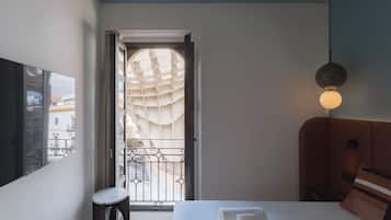 Une chambre d’hôtel avec un lit, une table de chevet, une lampe et une vue sur l’extérieur par une fenêtre.