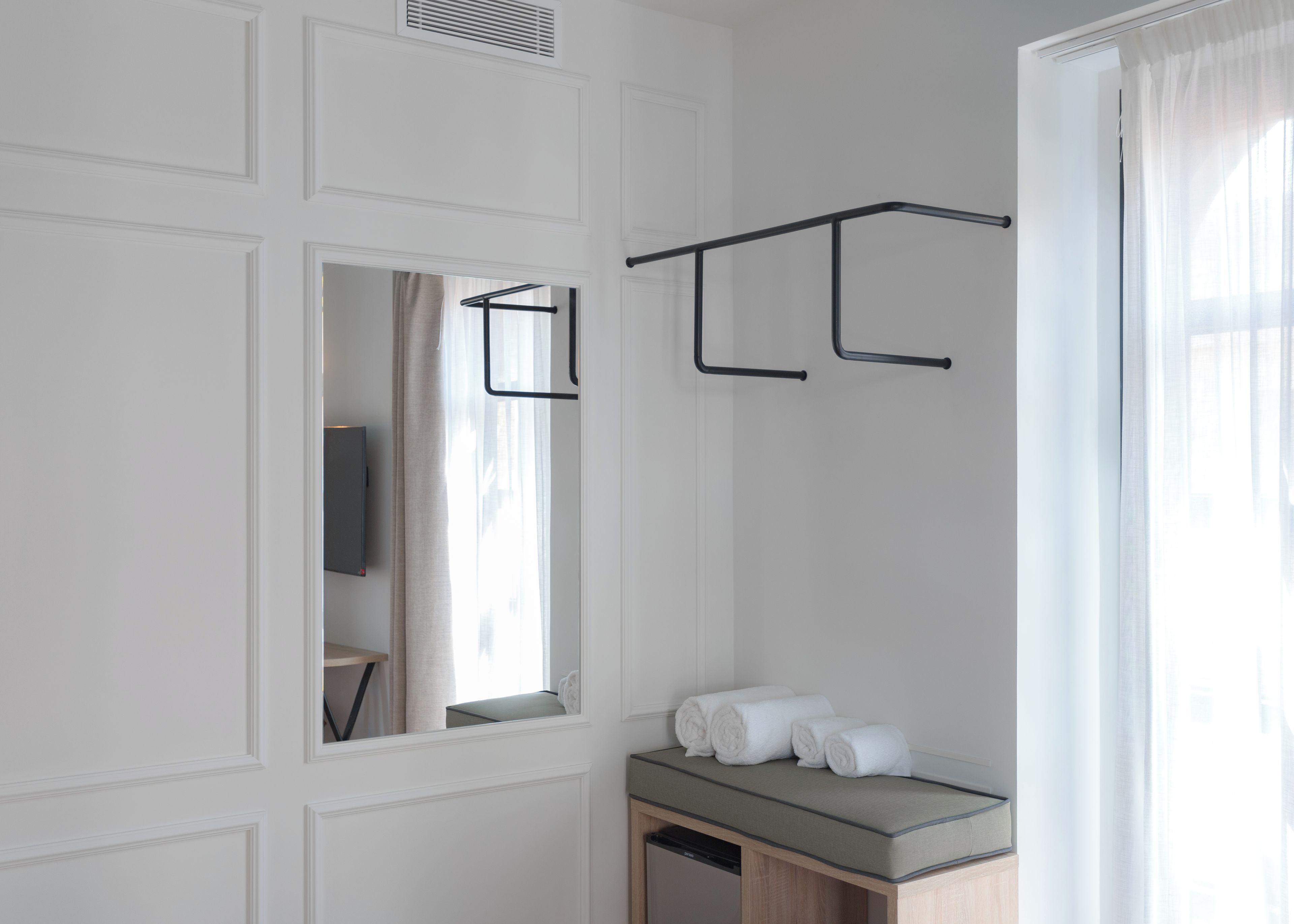 Une salle de bain avec un miroir, un porte-serviettes et un lavabo avec des serviettes.