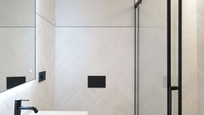 A modern bathroom with a white sink, toilet, and shower area. - Casa Candela Sevilla (Sevilla)
