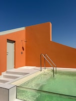 Un edificio moderno con una piscina, una porta e una scala che conduce alla piscina.