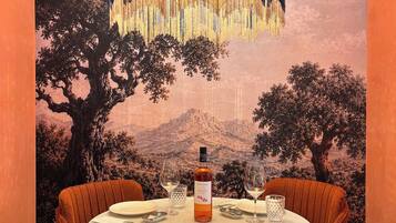 Un comedor con una mesa redonda, dos sillas, una botella de vino y dos copas.