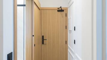 A hallway with a wooden door, a light switch, and a thermostat on the wall.