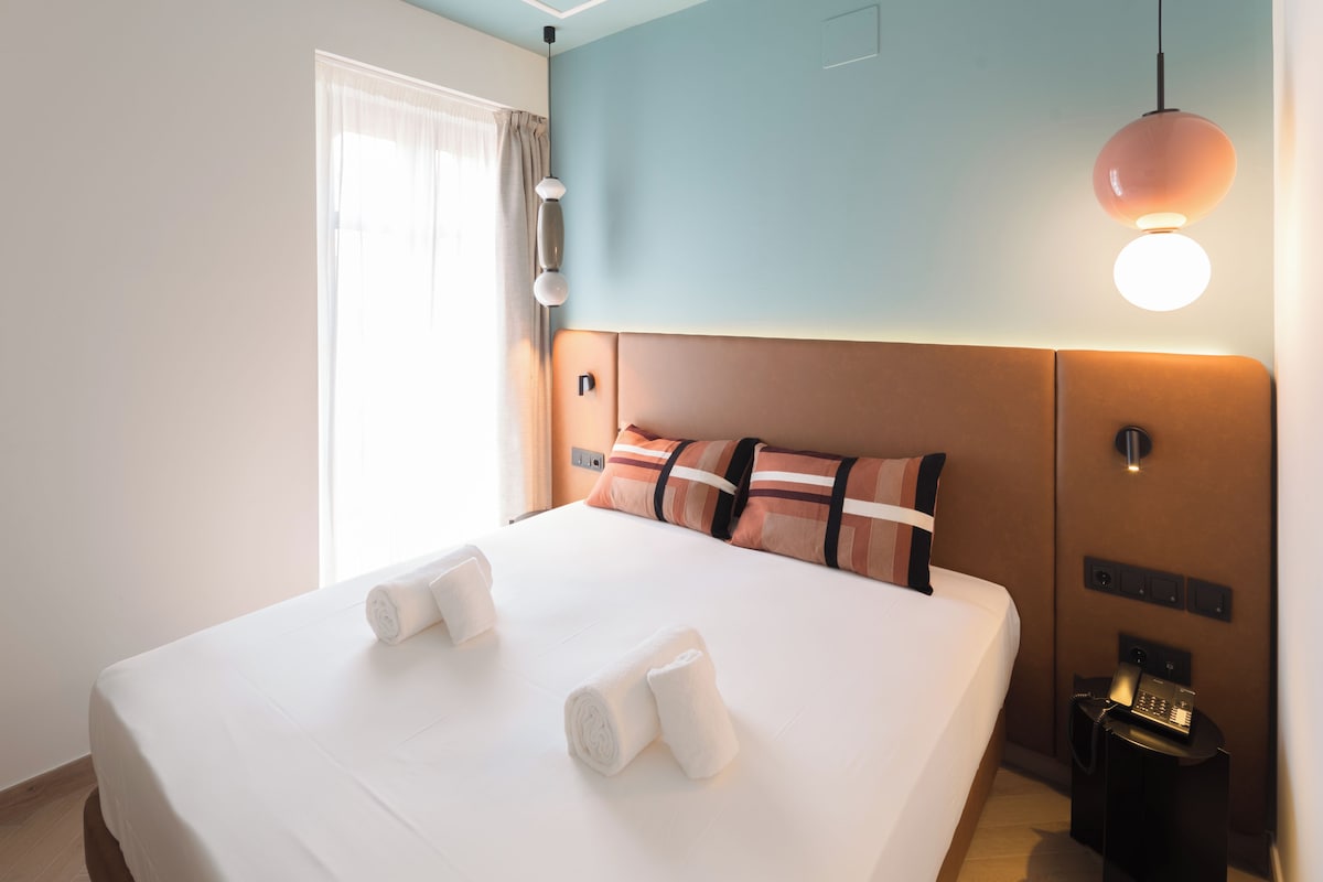 Ein Hotelzimmer mit einem großen Bett, einem Nachttisch mit Telefon und einer Wandleuchte.