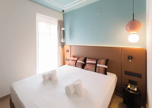 Ein Hotelzimmer mit einem großen Bett, einem Nachttisch mit Telefon und einer Wandleuchte.
