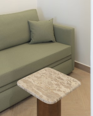 Ein grünes Sofa mit passender Kissen und einem kleinen Holztisch mit Marmoroptik.