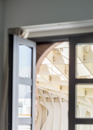 Puerta abierta que muestra el interior de una habitación, con una ventana y un techo con vigas estructurales.