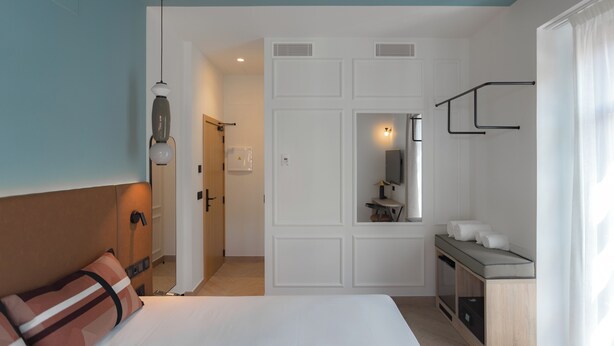 A hotel room with a bed, a desk with a mirror, a small kitchenette, and a bathroom visible through an open door. - Casa Candela Sevilla (Sevilla)