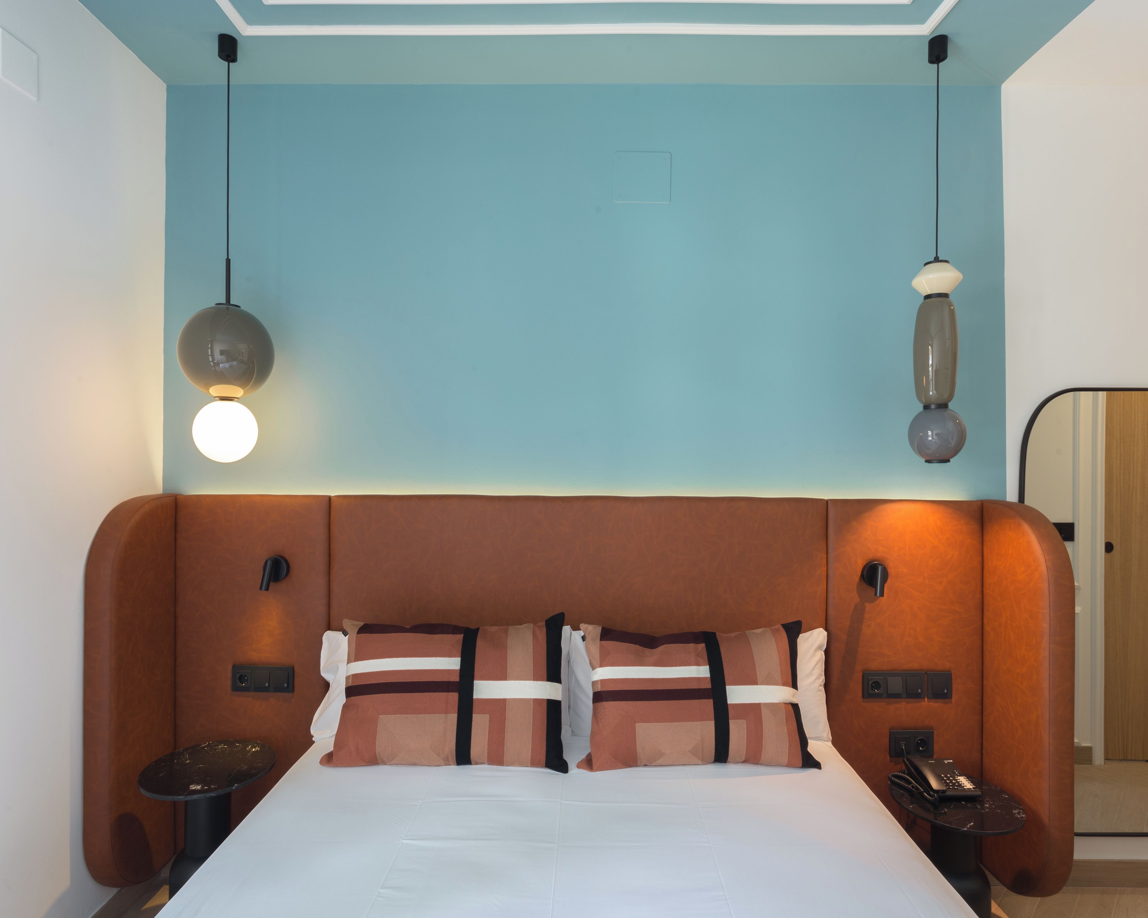 Ein Hotelzimmer mit einem großen Bett, zwei Nachttischen, einem Schminktisch, einem Spiegel und einer Deckenleuchte.