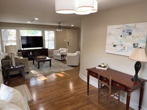 A living room with a television, sofa, chairs, and a desk with a lamp.