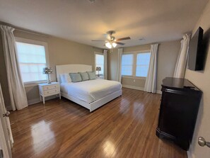 A bedroom with a bed, bedside tables, a ceiling fan, and a black cabinet.