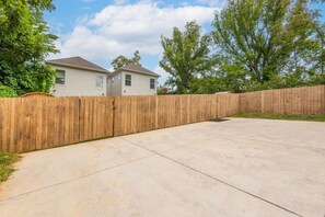 A residential area with a concrete driveway, wooden fence, and a house with a gabled roof. - Cowboy Cottage: Sleeps 12 (Nashville)