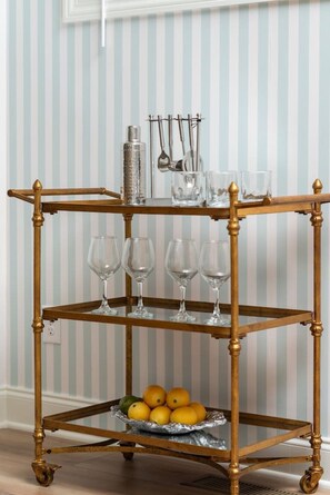 A gold-colored, three-tiered, wheeled cart with wine glasses and a fruit bowl. - Cowboy Cottage: Sleeps 12 (Nashville)