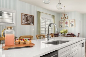 A modern kitchen with a large island, stainless steel sink, and a fruit platter. - Cowboy Cottage: Sleeps 12 (Nashville)