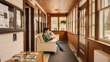 A corridor with wooden paneling, a sofa, a table with magazines, and a radiator.