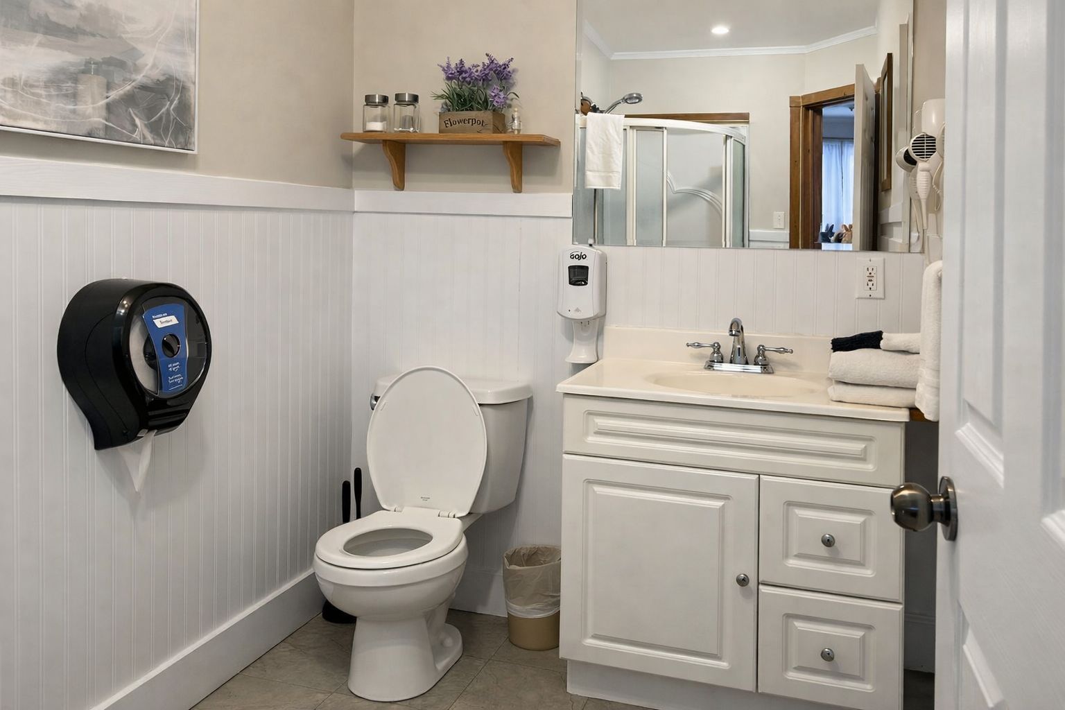 A bathroom with a toilet, a hand dryer, a sink, and a mirror.
