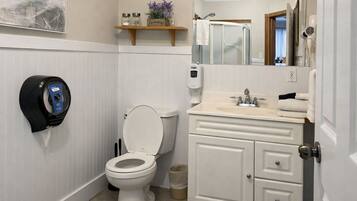 A bathroom with a toilet, a hand dryer, a sink, and a mirror.