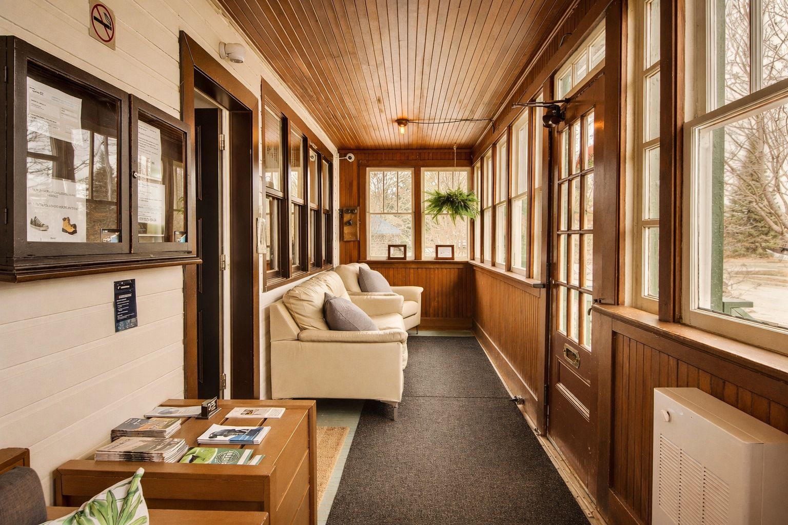 A corridor with a wooden ceiling, a beige sofa, and a table with magazines.