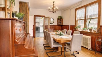 A dining area with a wooden table, chairs, a chandelier, and potted plants.