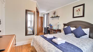 Une chambre d’hôtel avec un grand lit, un bureau, une chaise, une armoire et une salle de bain visible à travers une porte.