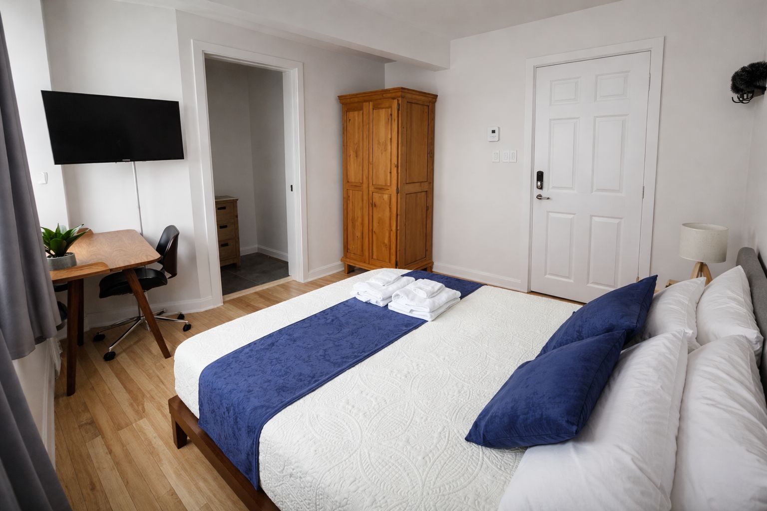 Una habitación de hotel con cama, escritorio, televisor y armario.