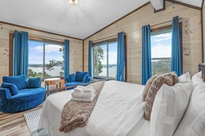 Een slaapkamer met een groot bed, een blauwe stoel en uitzicht op de omgeving.