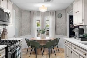 A modern kitchen with a central island, a stove, and a coffee machine.