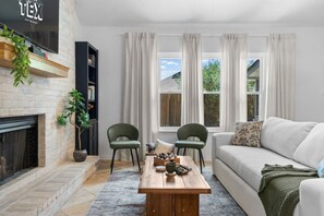 A living room with a fireplace, two green chairs, a wooden coffee table, and a white sofa.