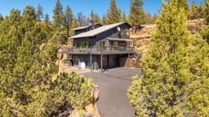 A two-story house with a balcony, surrounded by trees and a clear sky. - Cascade Views | Family Retreat | Dog Friendly (Sisters)