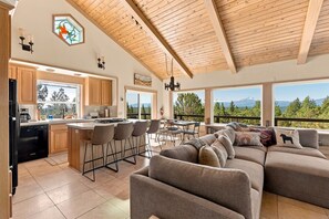 A modern kitchen with a bar area, large windows, and a view of mountains.