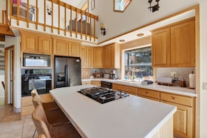 Una cocina con armarios de madera, una isla central, un refrigerador y una ventana con vistas.