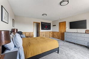 Un dormitorio con una cama, un aparador, un televisor y una puerta.