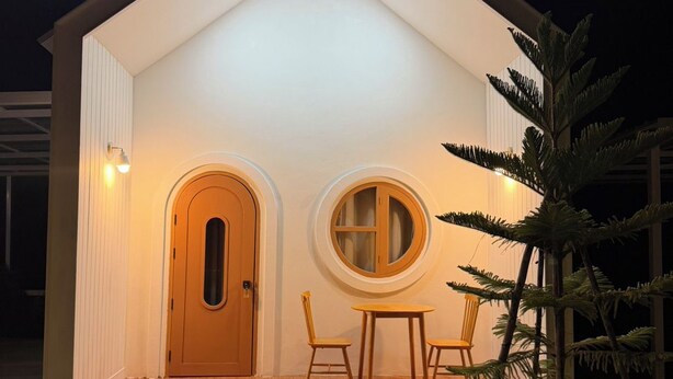 A small, single-story building with a front porch, two doors, and a round table with chairs. - Lesiri hotel (Yang Si Surat)