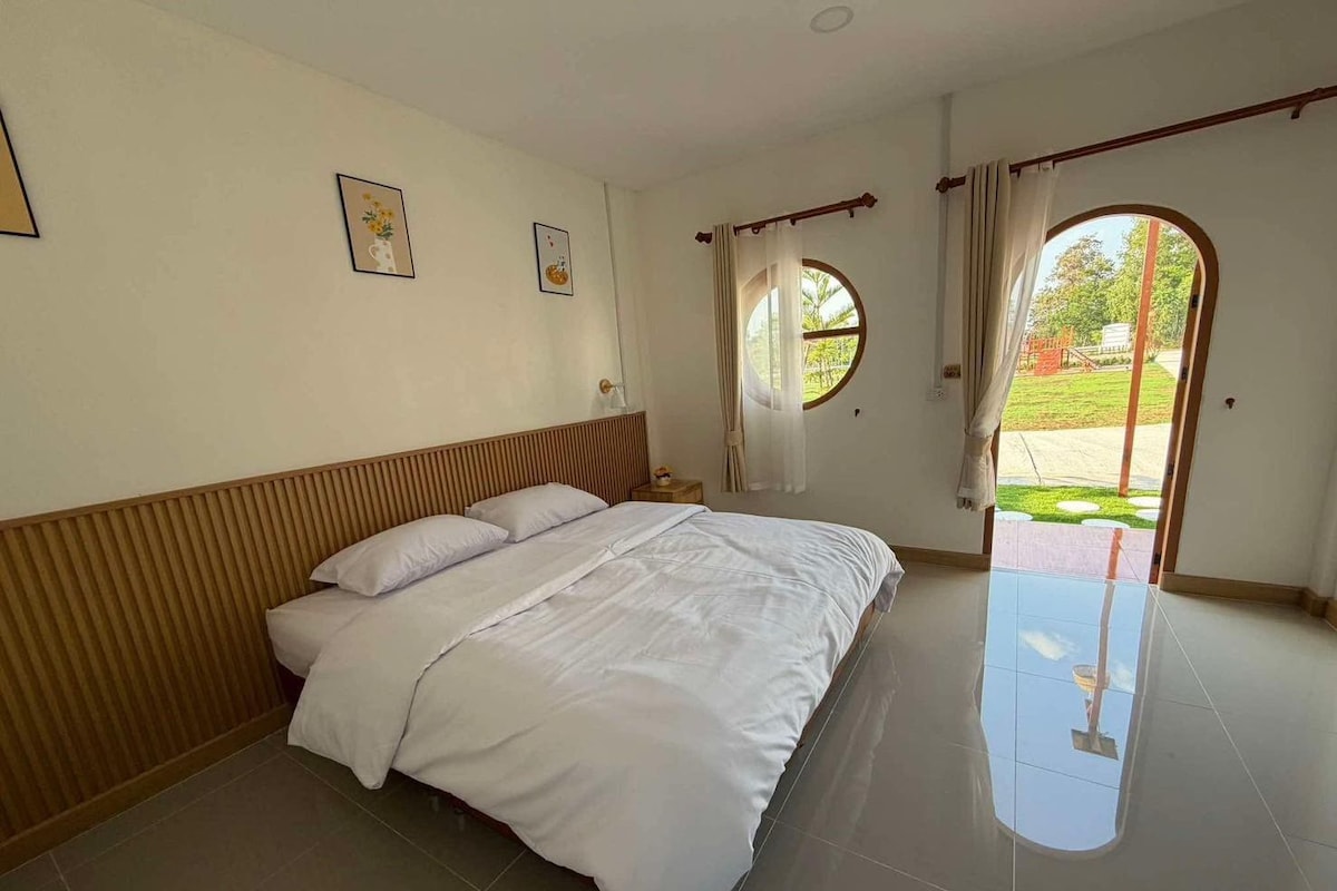 Une chambre d’hôtel avec un lit, une table de chevet, une fenêtre avec des rideaux et une vue sur l’extérieur.