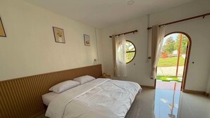A hotel room with a bed, a nightstand, a window with curtains, and a view of the outdoors. - Lesiri hotel (Yang Si Surat)