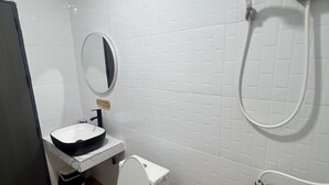 A bathroom with a white toilet, a sink, and a mirror. - Lesiri hotel (Yang Si Surat)