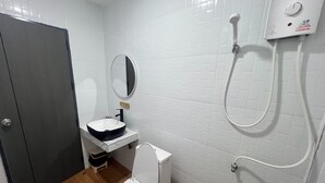 A bathroom with a white toilet, a sink with a black basin, a mirror, and a shower unit. - Lesiri hotel (Yang Si Surat)