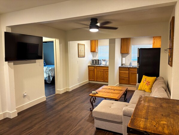 A living room with a sofa, coffee table, and a television mounted on the wall.