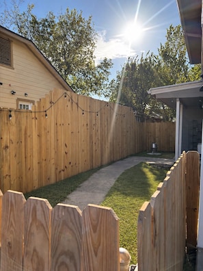 A wooden fence, a pathway, and a building with a garage.