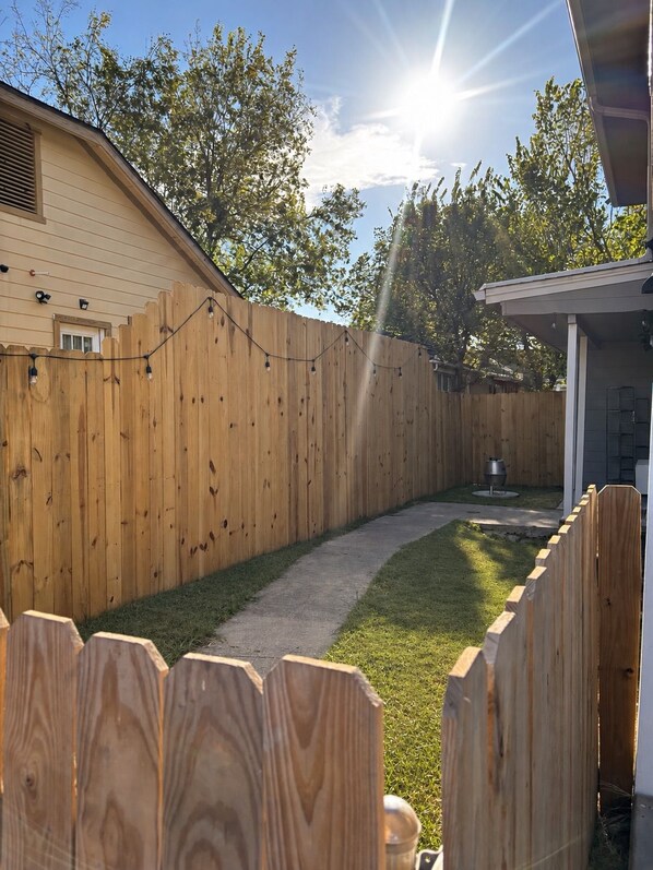 A wooden fence, a pathway, and a building with a garage.