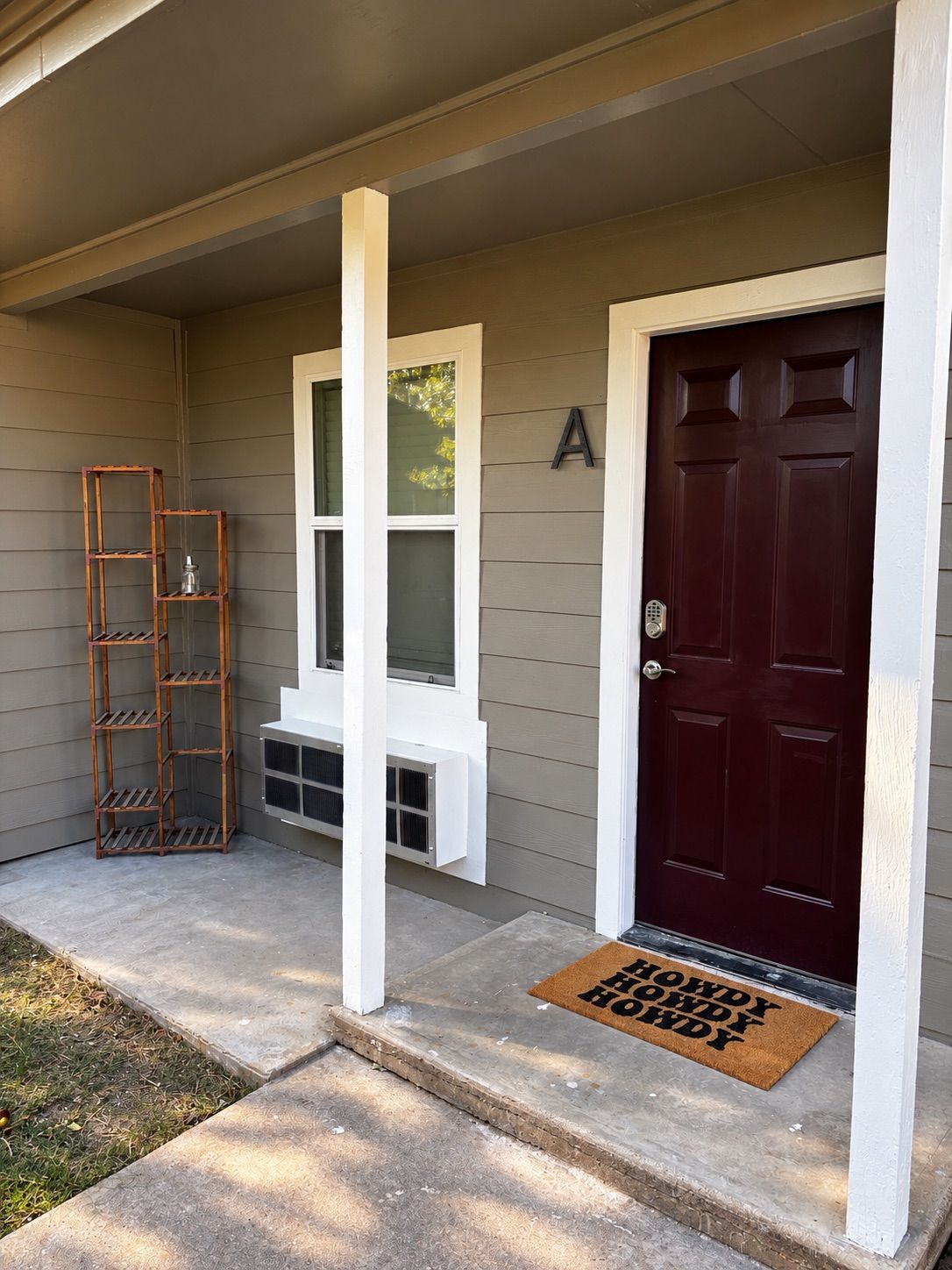 A house entrance with a dark red door, a white mailbox, and a wooden ladder.