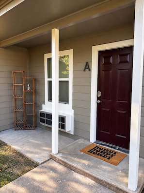 A house entrance with a dark red door, a white mailbox, and a wooden ladder.