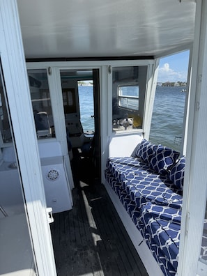 A narrow passageway leading to a small cabin area with a bed and a window overlooking the water.