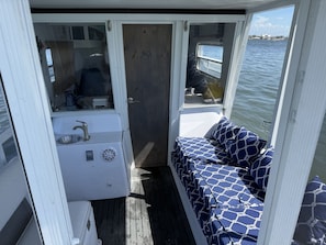 A compact cabin with a small sink, a window, and a cushioned seating area.